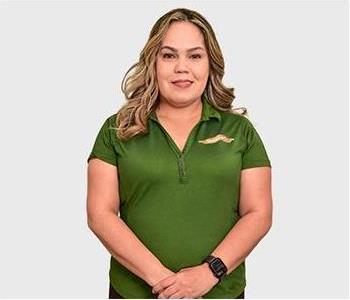 Female in navy polo standing in front of light background