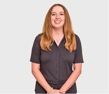 Female in navy polo standing in front of light background